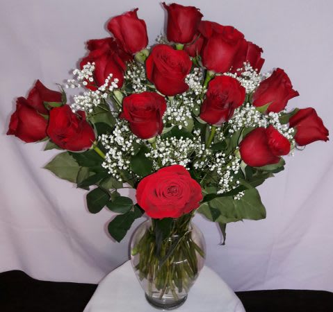 Bouquet of red roses with baby's breath in a clear glass vase