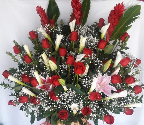 Tall basket arrangement of red roses, white calla lilies, and pink lilies with baby’s breath