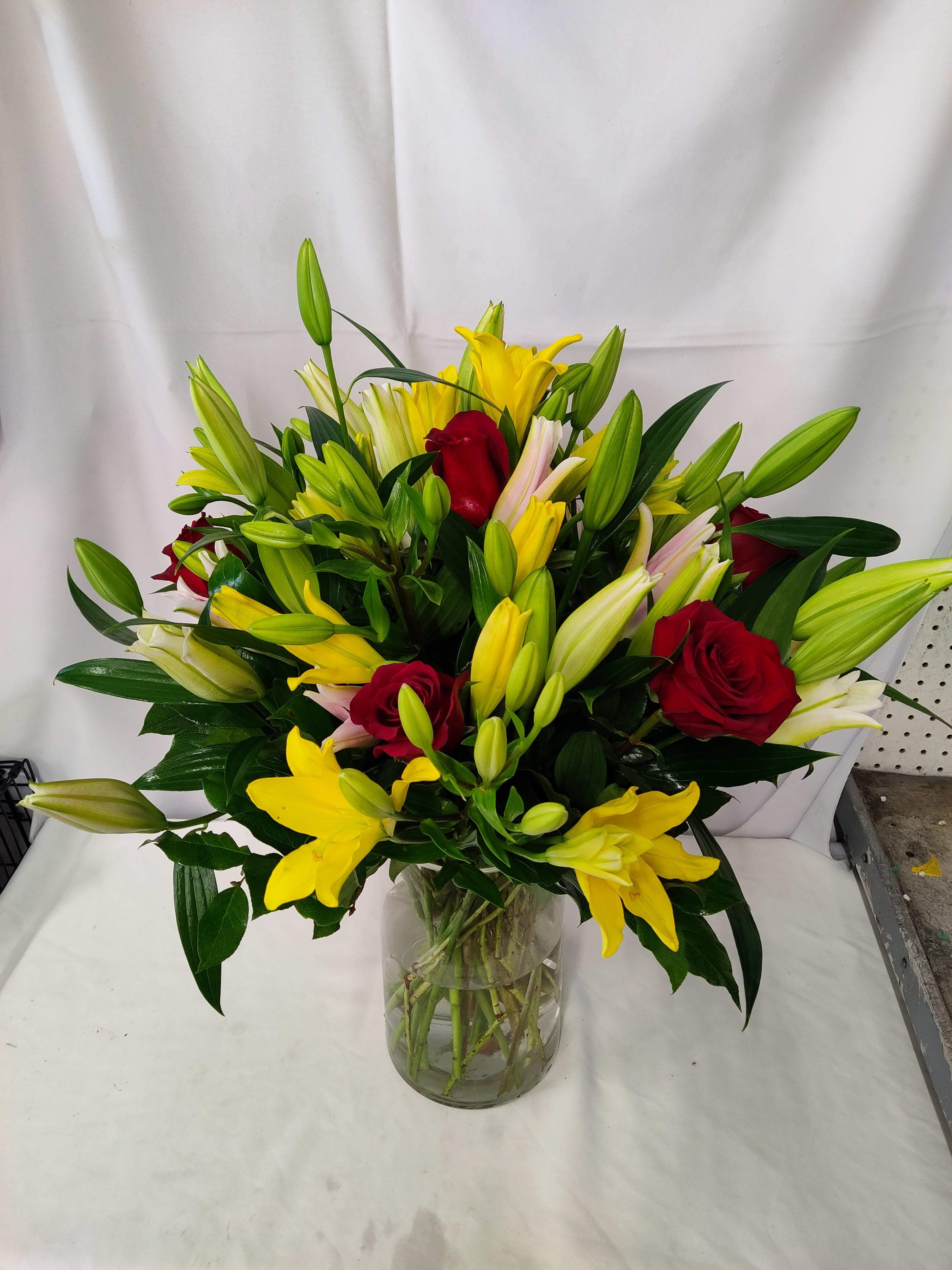 Bouquet of yellow lilies and red roses in a clear glass vase