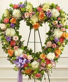 Large floral wreath on a black easel with a purple ribbon