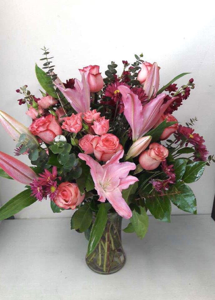 Pink roses and lilies arranged in a clear glass vase
