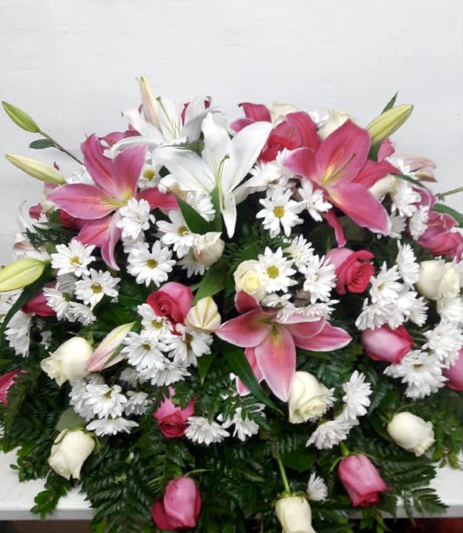 Pink lilies, white daisies, and roses arranged in a dense bouquet