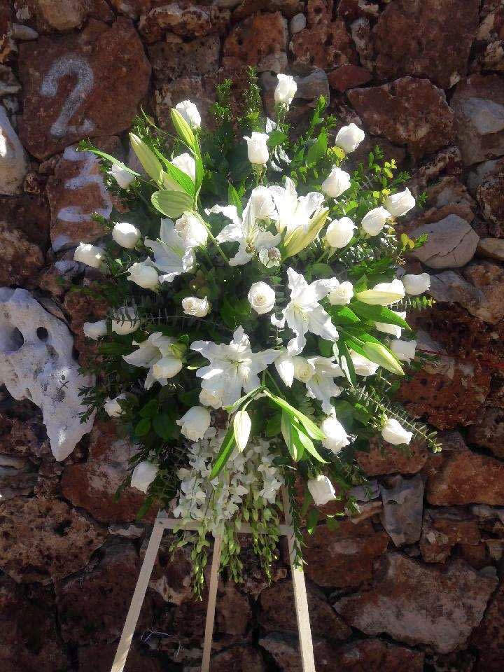White floral standing spray with lilies and roses on an easel