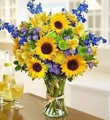 Bouquet of sunflowers and blue flowers in a glass vase