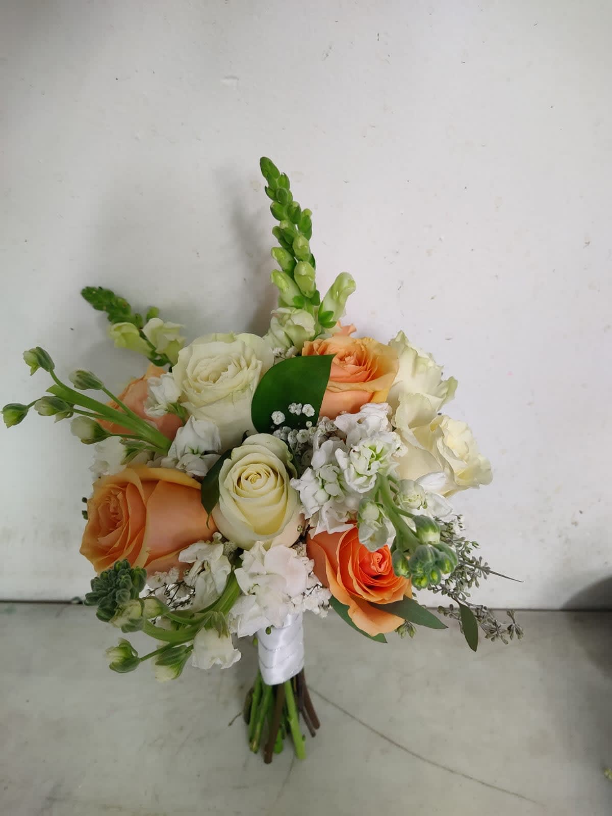 Sunshine wedding bouquet  - This wedding bouquet includes orange and white roses with greenery included and white snap dragons as filler. This is an amazing bouquet for a summer, spring and even fall weddings.