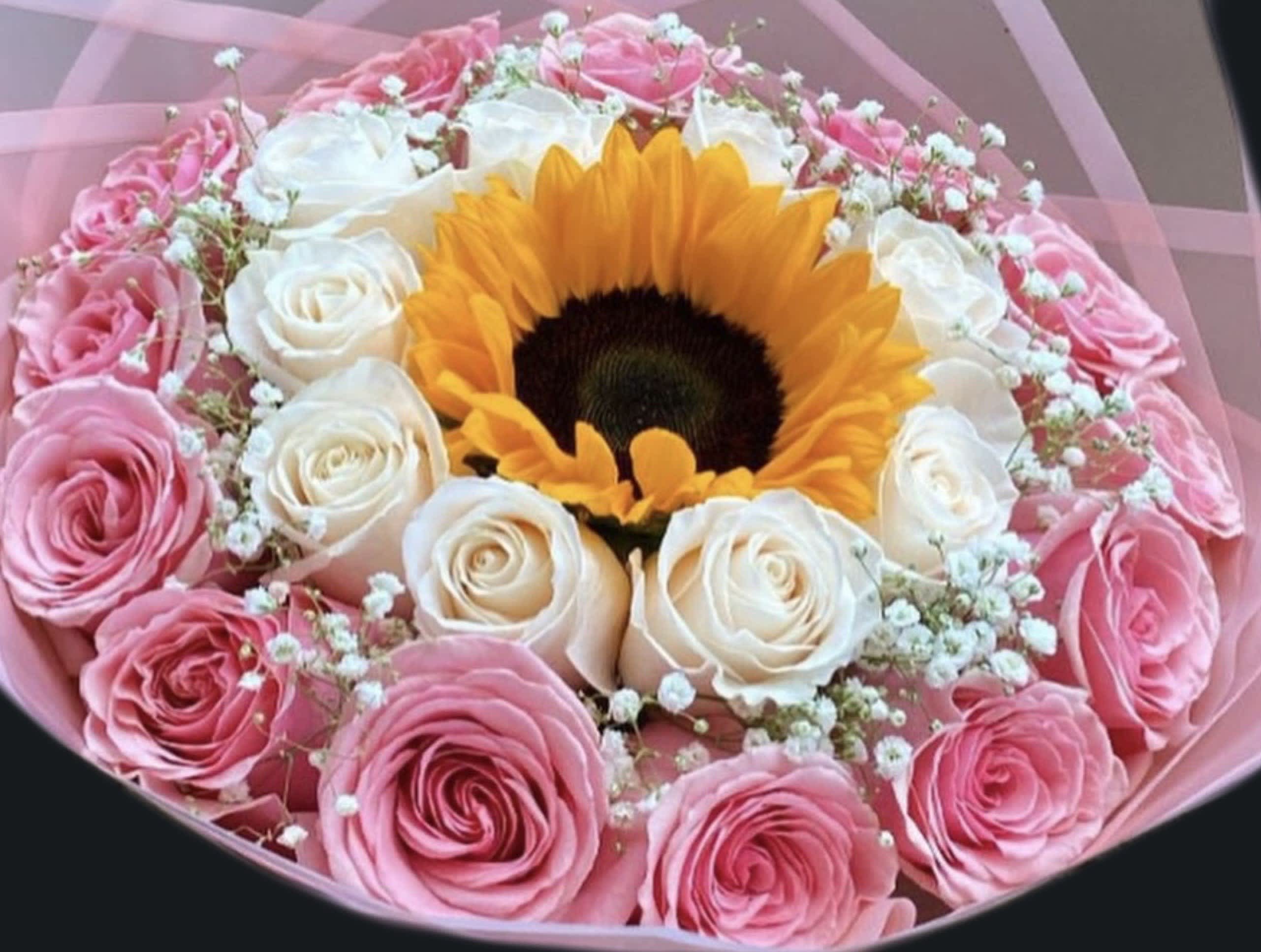 Pink and white roses arranged around a sunflower bouquet