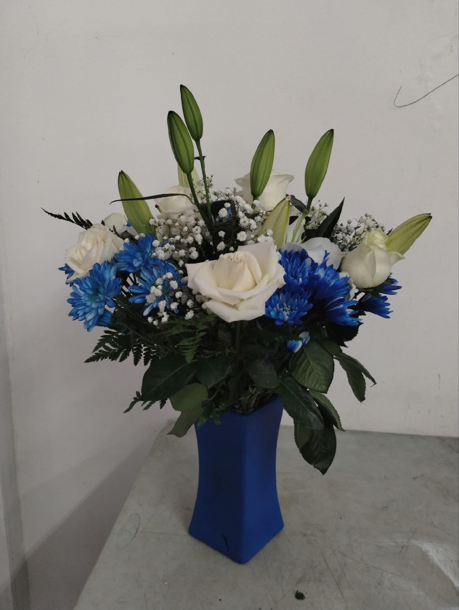 White roses and blue flowers in a blue vase
