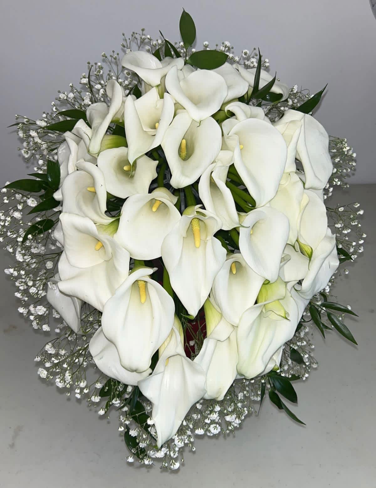 Bouquet of white calla lilies with baby's breath and greenery