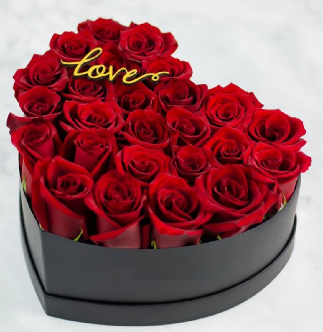 Heart-shaped box of red roses with a gold "love" topper
