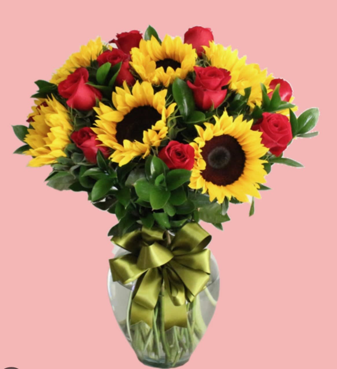 Bouquet of red roses and yellow sunflowers in a glass vase with a ribbon