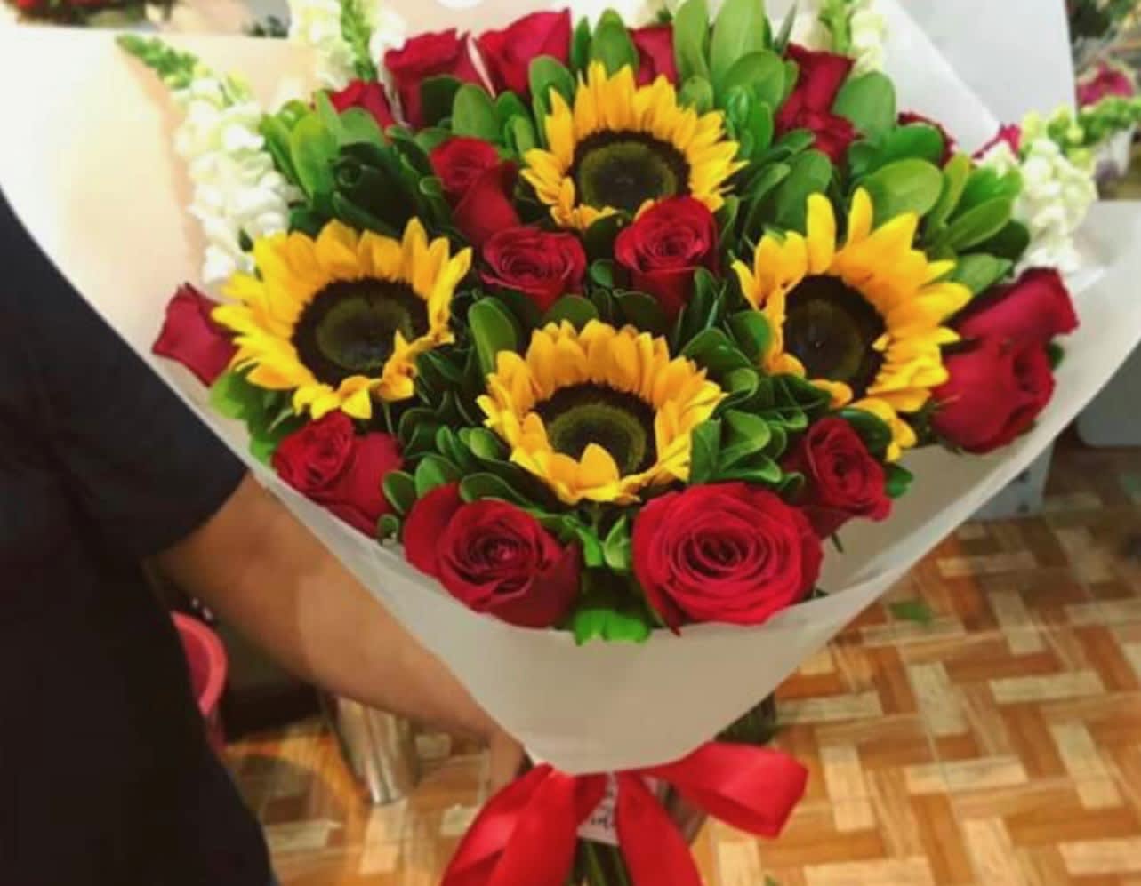 Bouquet of red roses and sunflowers wrapped in white paper