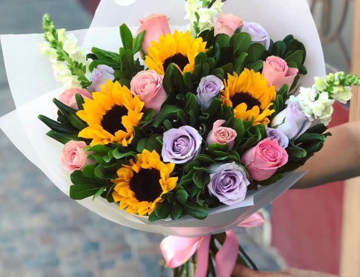 Bouquet of sunflowers and pastel roses wrapped in white paper