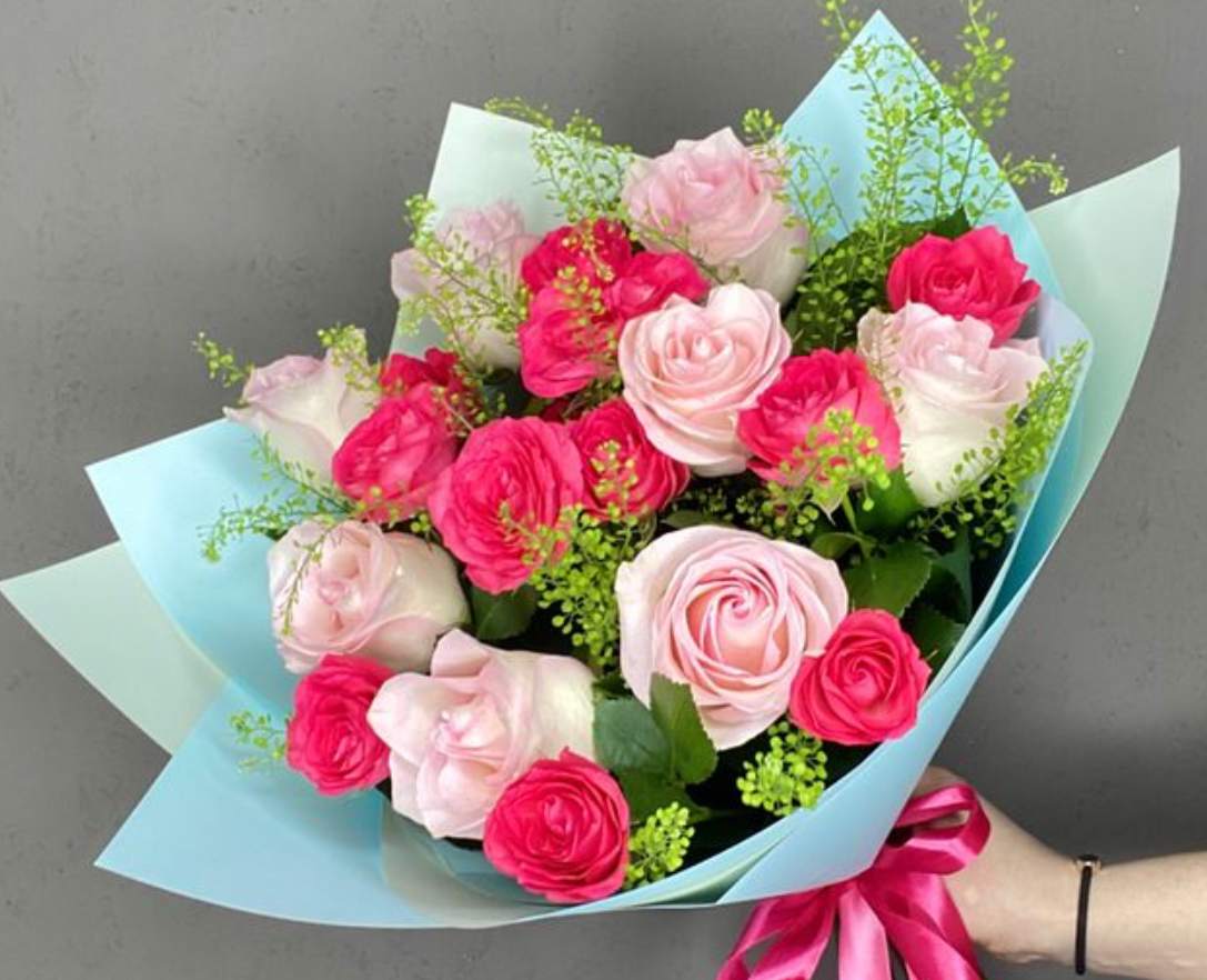 Bouquet of pink and white roses wrapped in light blue paper