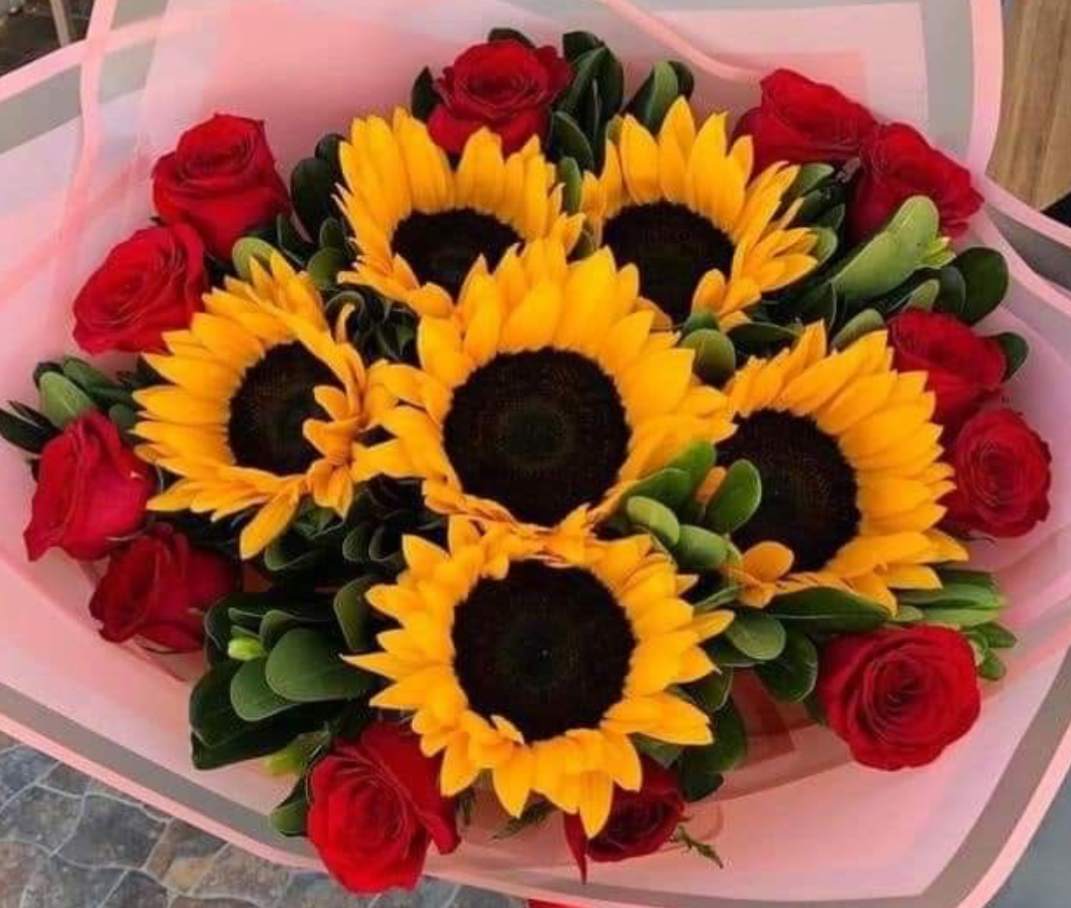 Bouquet of sunflowers and red roses wrapped in pink paper