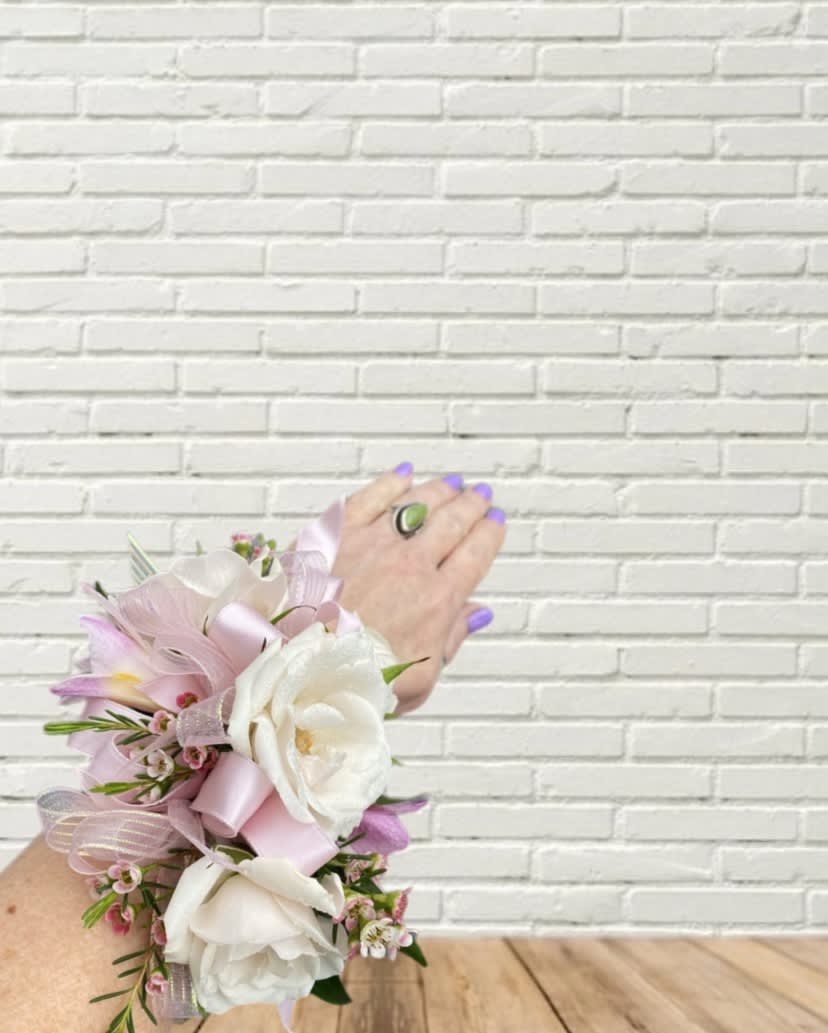 Pink and white floral wrist corsage with ribbon on a hand