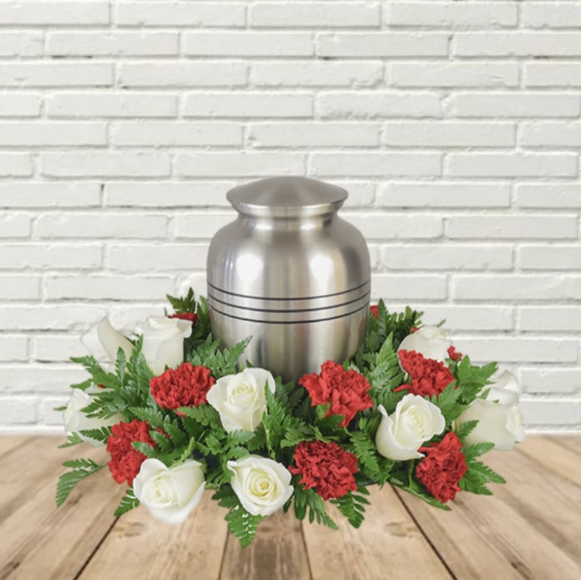 White roses and red carnations arranged around a silver urn