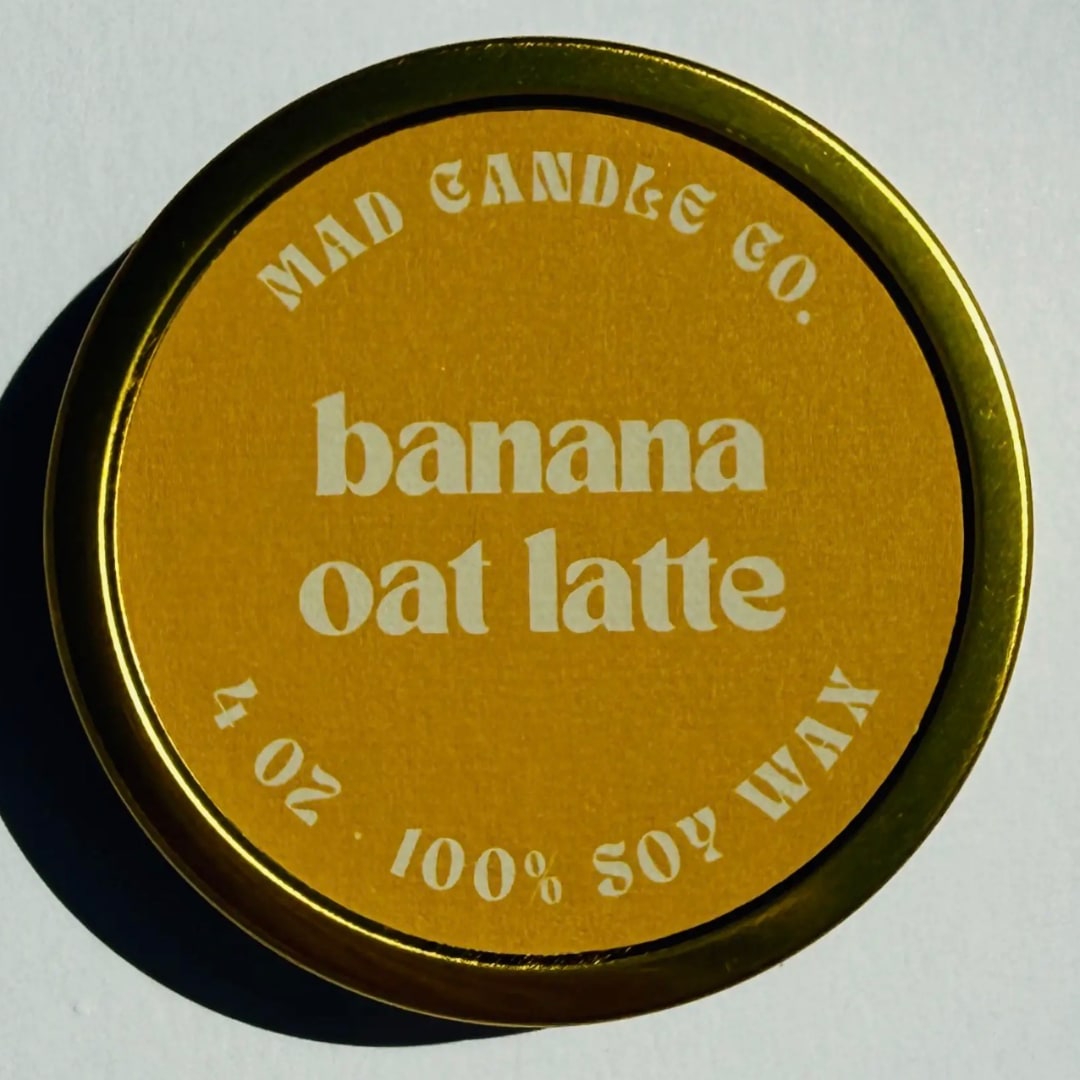 Banana Oat Latte Soy Candle - 4oz Travel Tin &amp; Wood Wick - caramelized banana • toasted pecans • oat foam • cinnamon dust  Product Information: Our 4 oz Gold Metal Travel Tin candles are hand-poured in Eugene, Oregon, featuring sleek gold tins with a polished finish and a matching gold metal lid. These compact, handmade candles offer a generous 15-20 hour burn time, perfect for on-the-go use. Dimensions: 3.25" W x 1.25" H. Ideal for retail displays, gift shops, and travel enthusiasts.  The entire Mad Candle Co. collection is made with only the best ingredients in the industry including 100% domestically-grown soy wax, clean fragrance oils, and sustainable FSC-certified wood wicks. The fragrances we use are vegan, paraben-free, and phthalate-free.