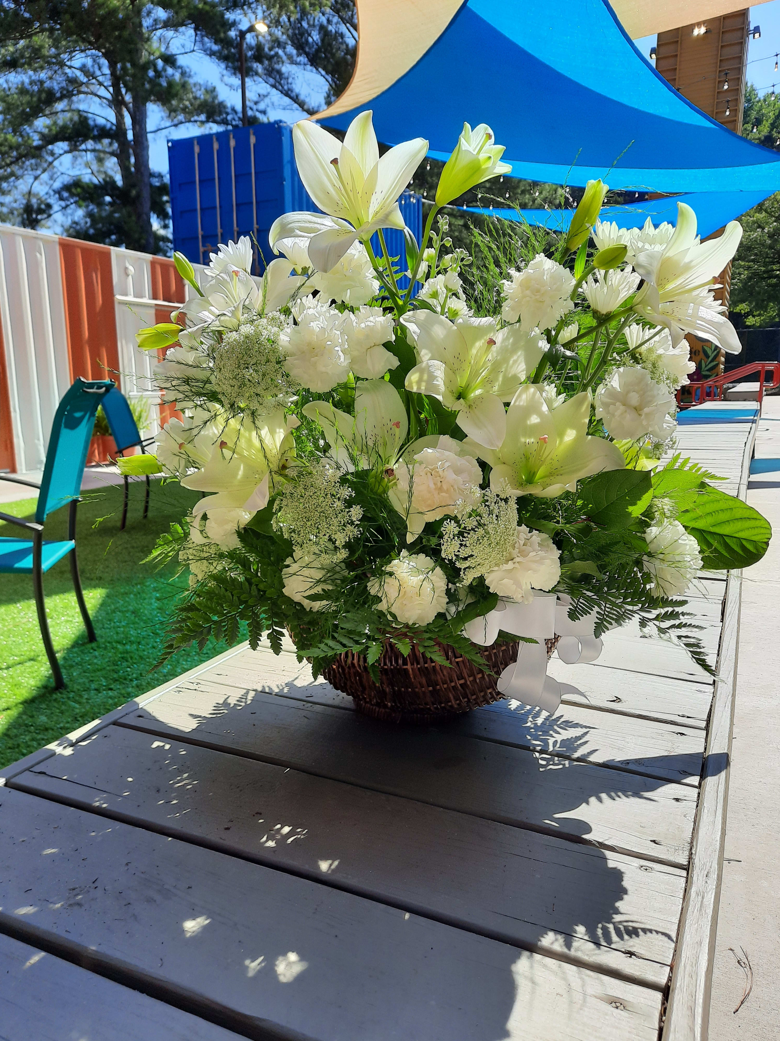 White lilies and carnations arranged in a wicker basket