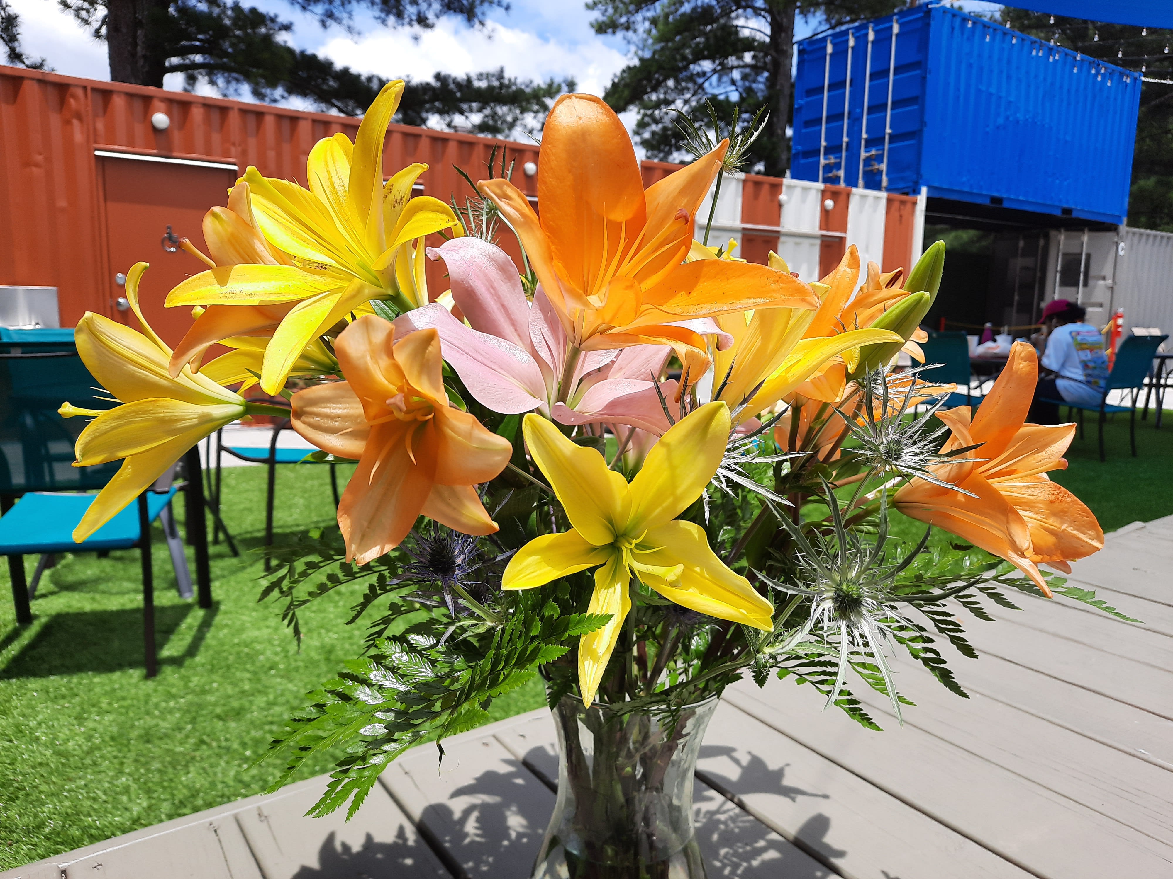 Bouquet of yellow, orange, and pink lilies in a glass vase