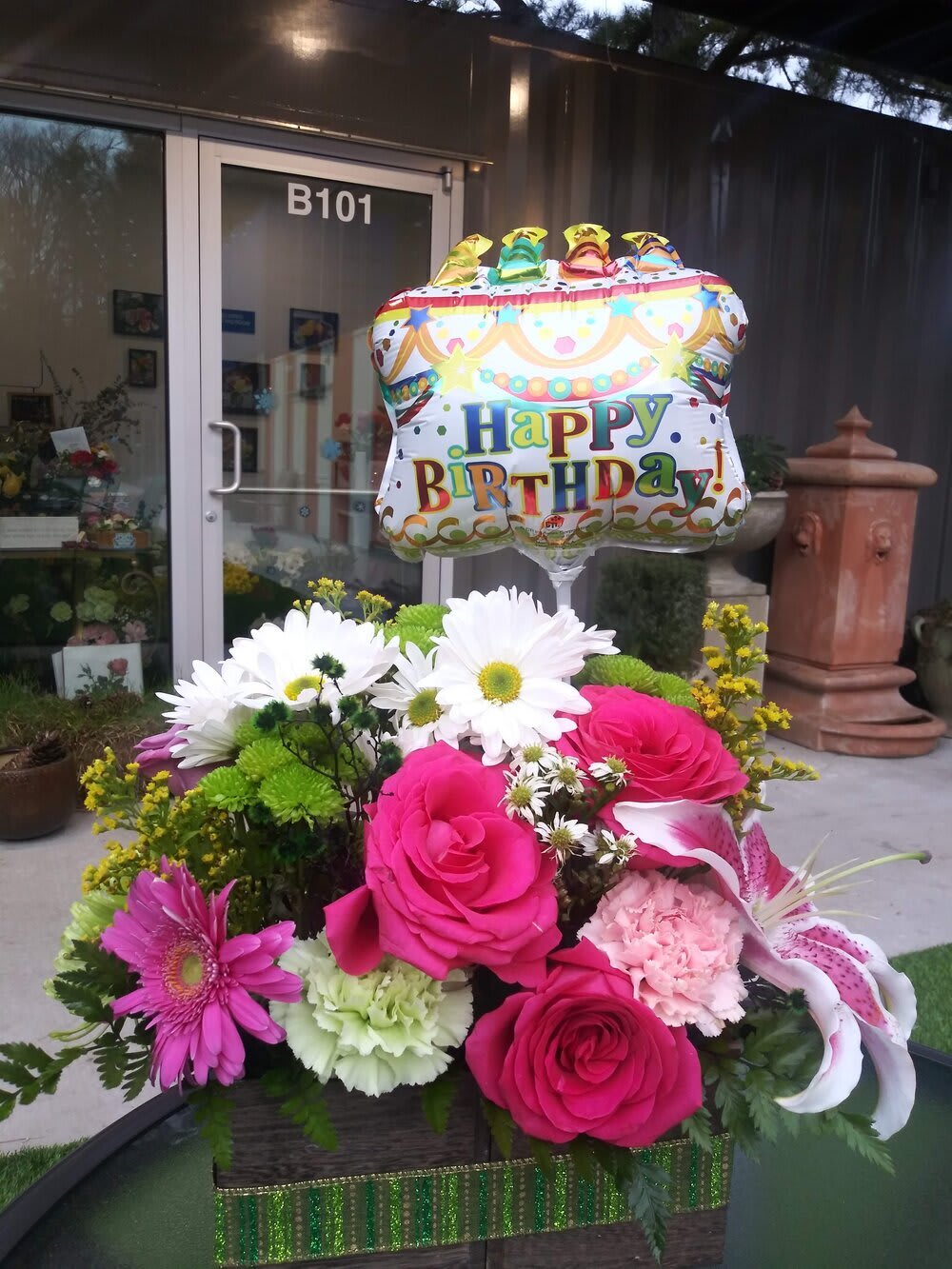 Birthday balloon above a colorful flower arrangement in a basket