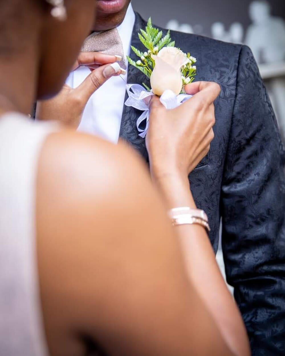 Person pinning a white rose boutonniere onto a man's suit jacket