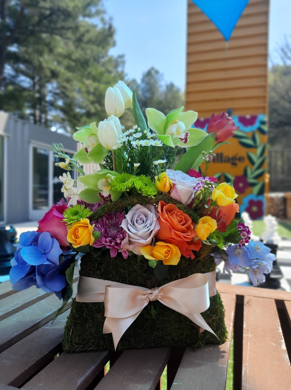 Colorful floral arrangement with roses, orchids, tulips, and hydrangeas on a moss base
