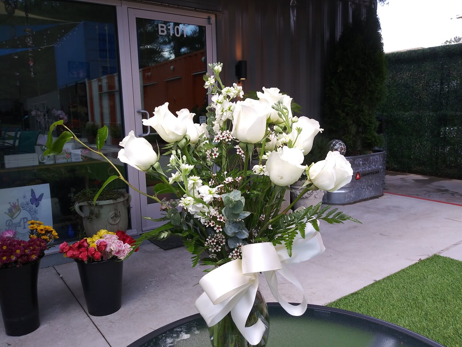 White rose bouquet in a glass vase with a white ribbon