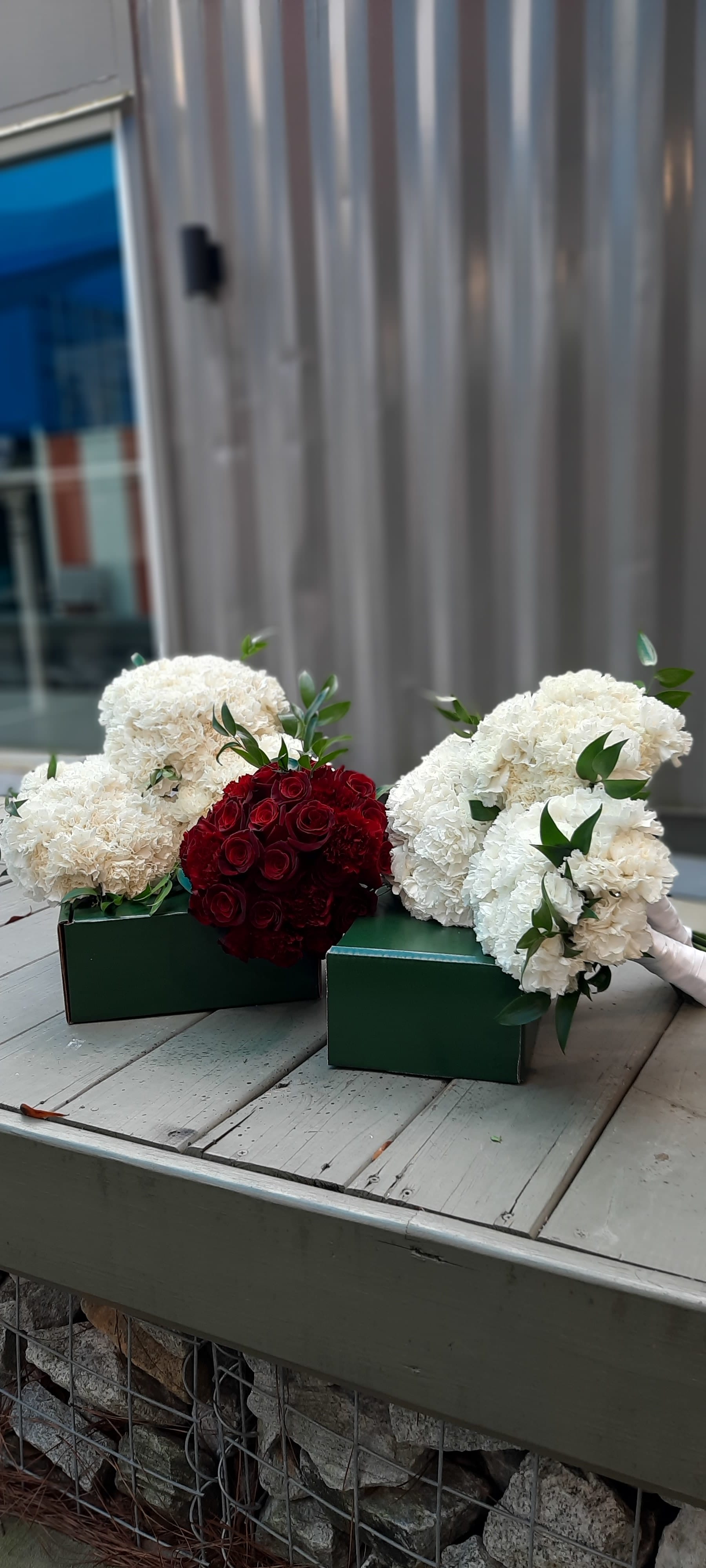 Bouquets of white carnations and red roses in green boxes