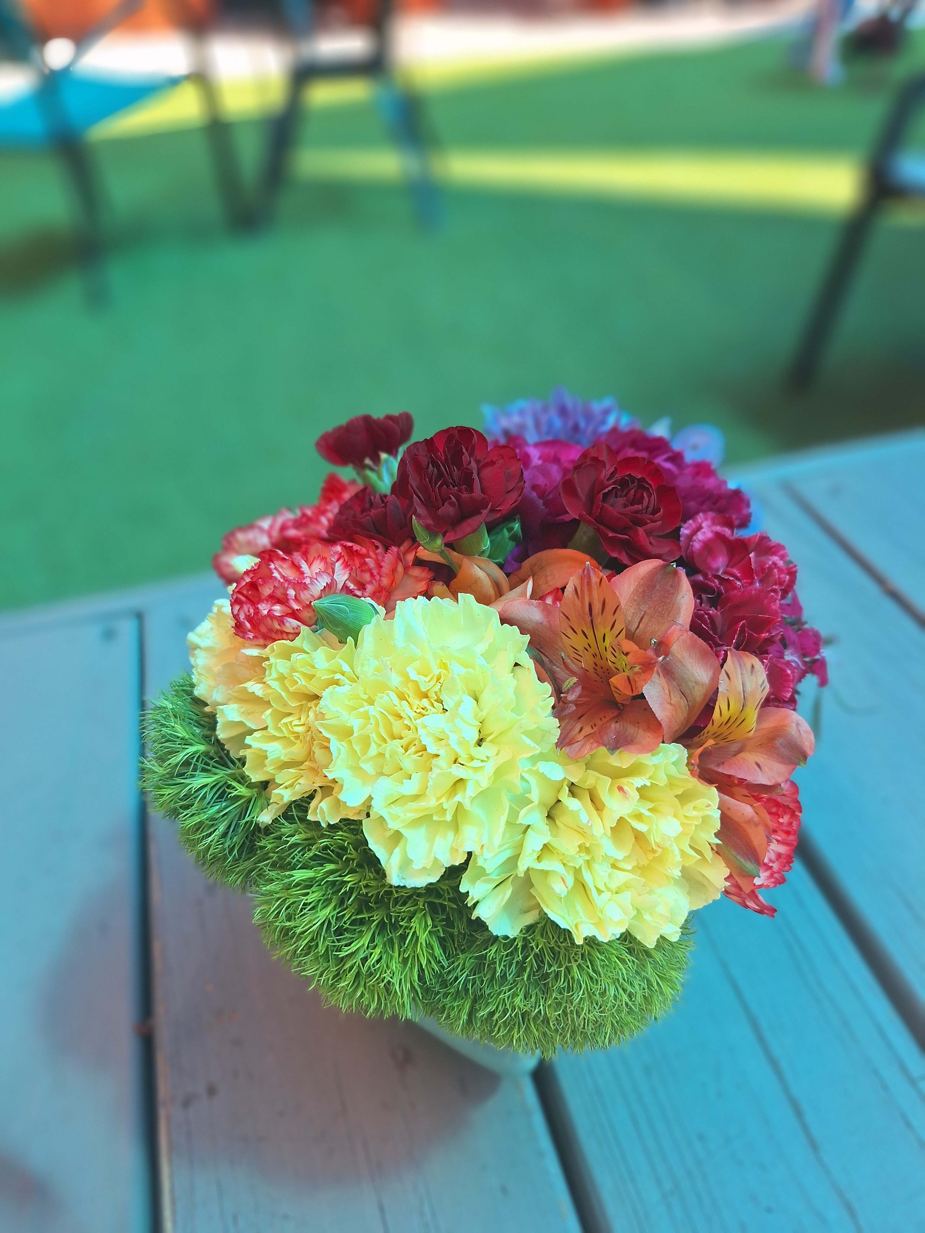Colorful bouquet with carnations and alstroemeria in a green textured base