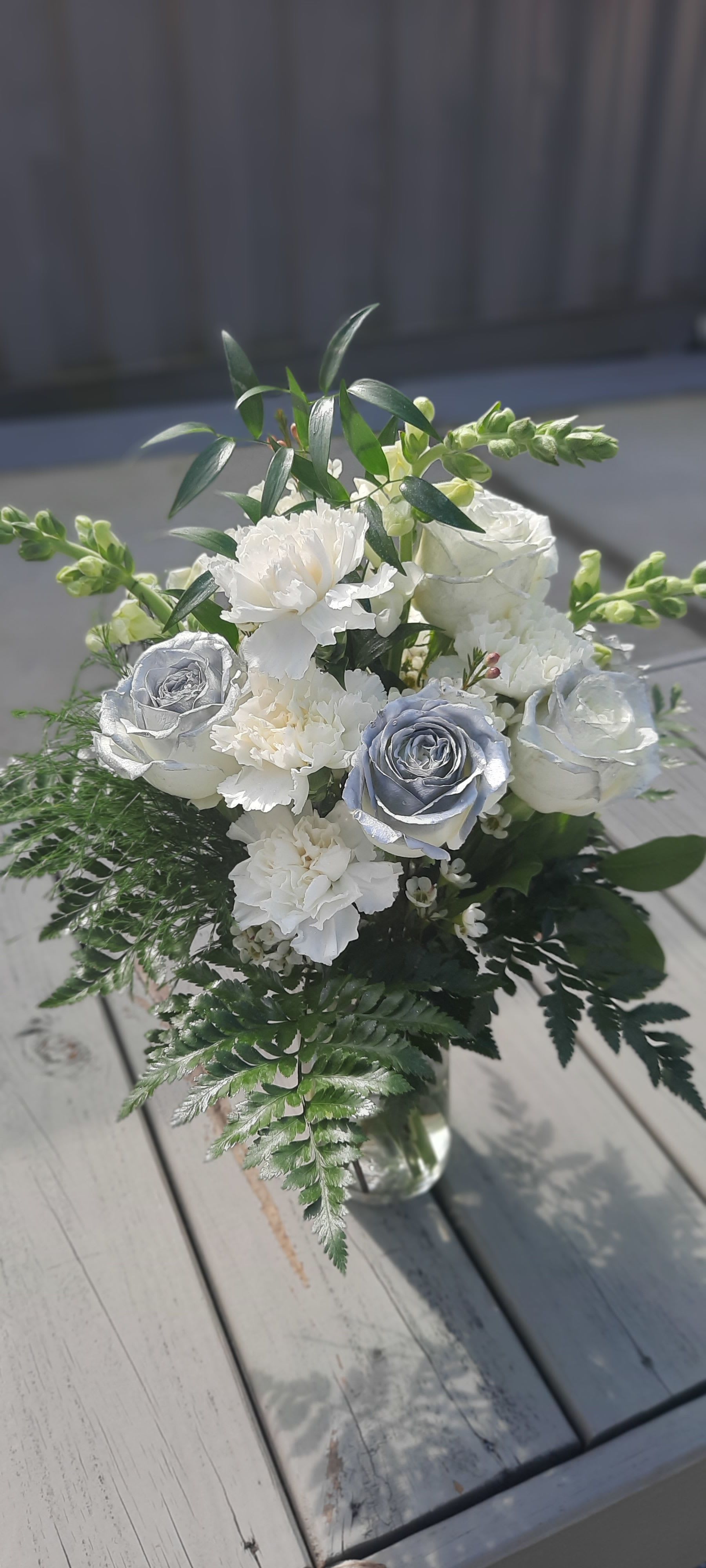 White and silver rose bouquet with carnations in a glass vase