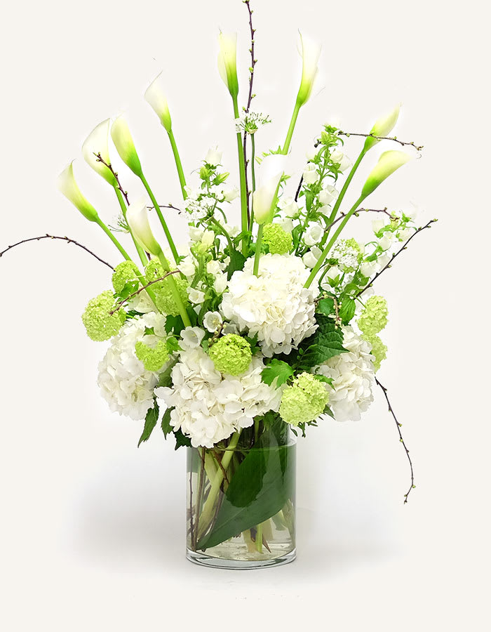 The Serenity - Whether you’re sending someone a romantic gift or expressing condolences, this understated bouquet is the way to do it. We’ve paired dazzling white calla lili with white hydrangeas  and chrysanthemums, all contrasted with luscious greenery. Simple yet perfect.