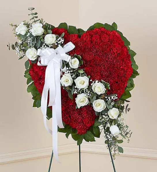 Floral Heart Tribute Red with White Roses - Honor a loved one with a special tribute. Our heart-shaped standing arrangement of fresh red carnations, accented by a cascading sash of white roses adorned with a white satin ribbon, will help you elegantly express your sincere devotion and sympathy.Arrangement of red carnations, white roses, gypsophila, spiral and seeded eucalyptus, salal and variegated pittosporum; accented with a white satin ribbon