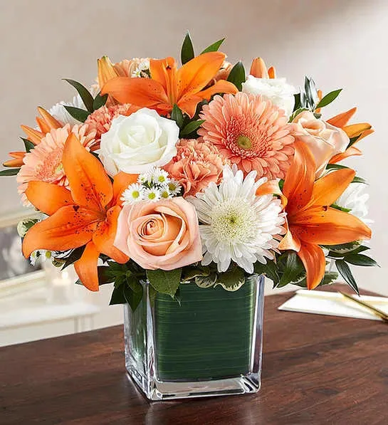 Healing Tears Peach  Orange &amp; White - Sometimes it’s simply the savoring of warm memories that helps ease the pain of loss. Our sympathy arrangement of peach roses, daisies, orange lilies and white roses, expertly gathered in a clear glass cube lined with a Ti leaf ribbon, makes for a sweet and sentimental gesture of remembrance and healing.