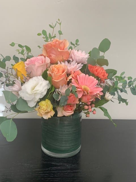 Mixed bouquet of pastel flowers in a green glass vase