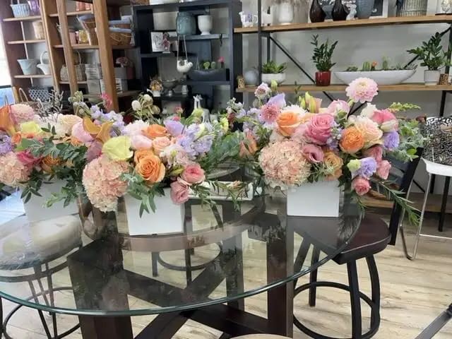 Pastel floral arrangements in white boxes on a glass table