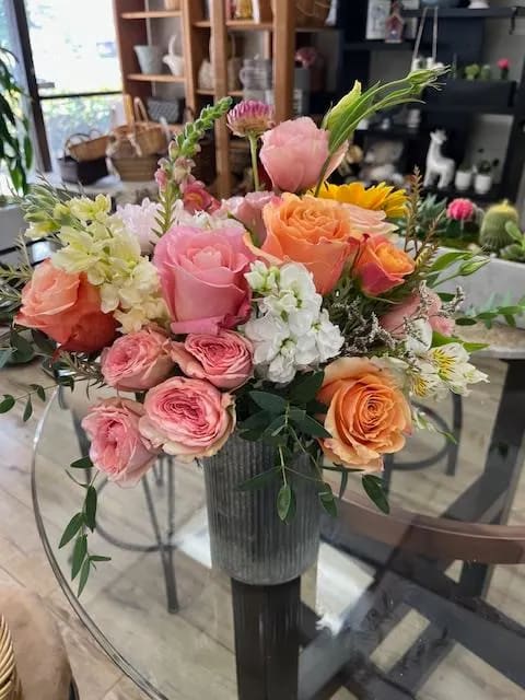Mixed pink, peach, and white flower arrangement in a gray vase