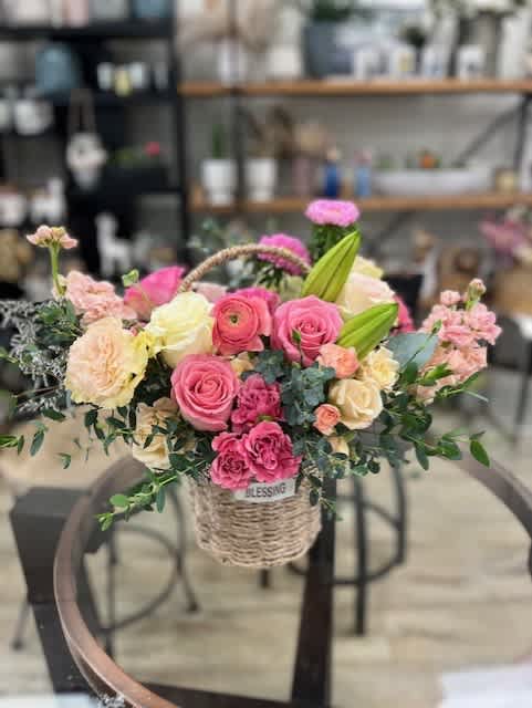 Basket arrangement of pink and cream roses with lilies