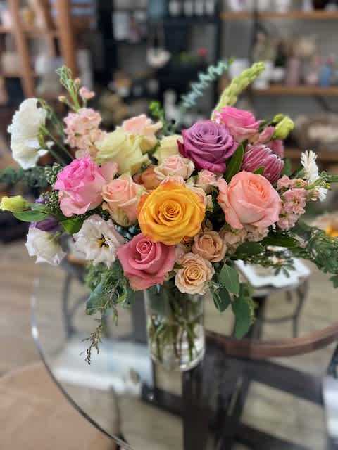 Mixed bouquet of roses and other blooms in a glass vase