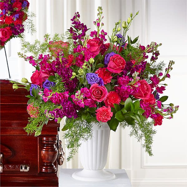 Bright pink and purple floral arrangement in a white vase