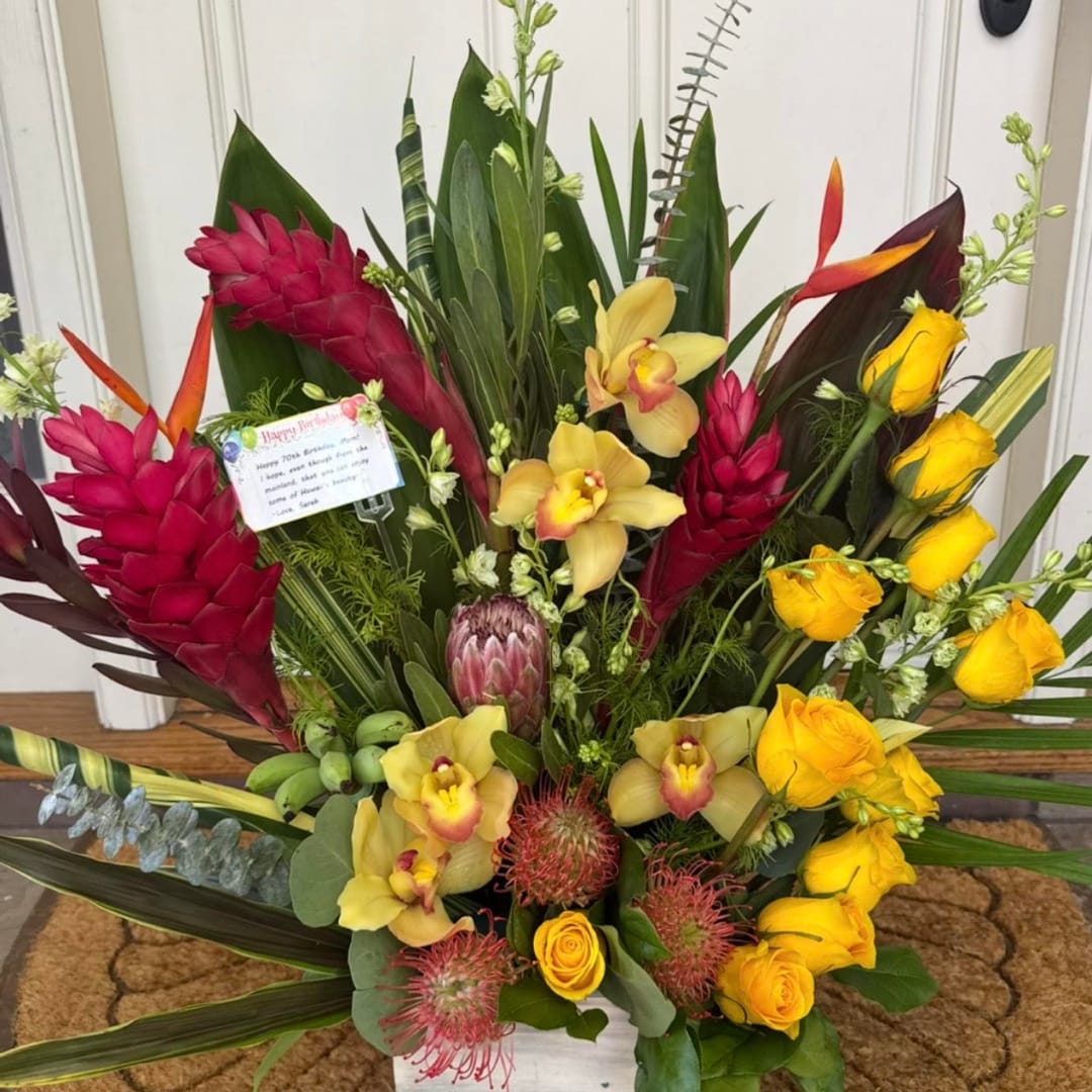 Tropical bouquet with yellow orchids, red ginger, and yellow roses in a white container