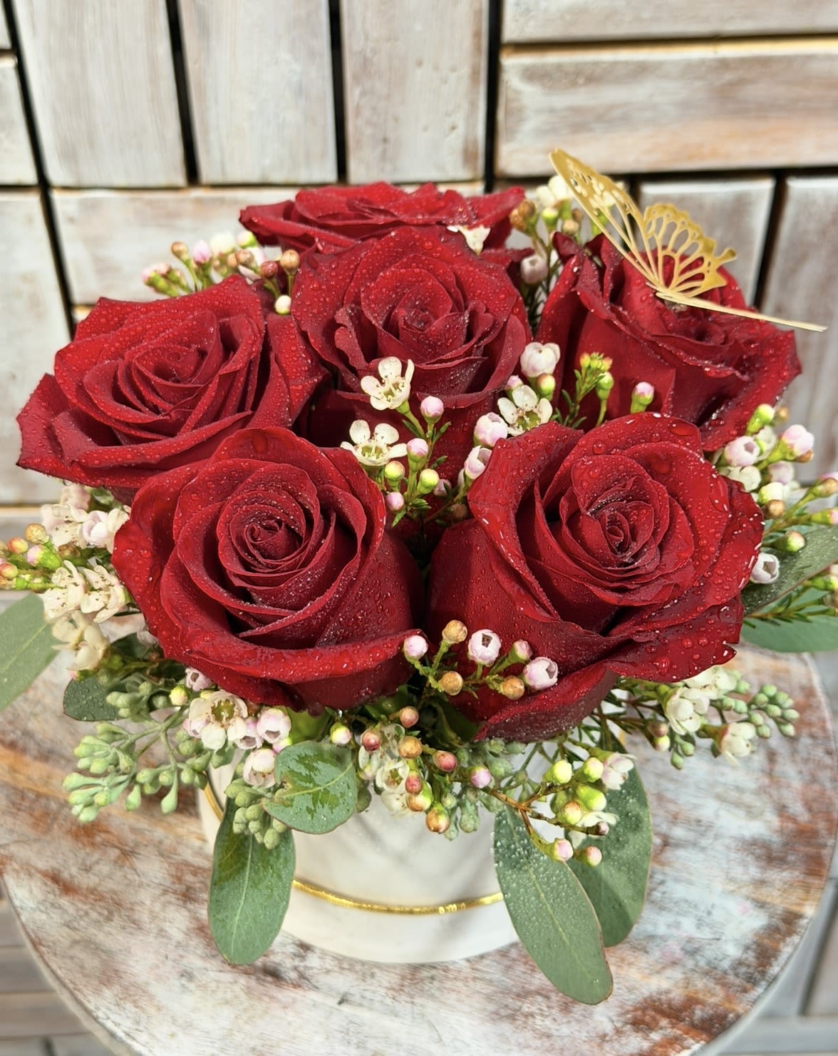 Red roses arranged in a white hat box with small white filler flowers