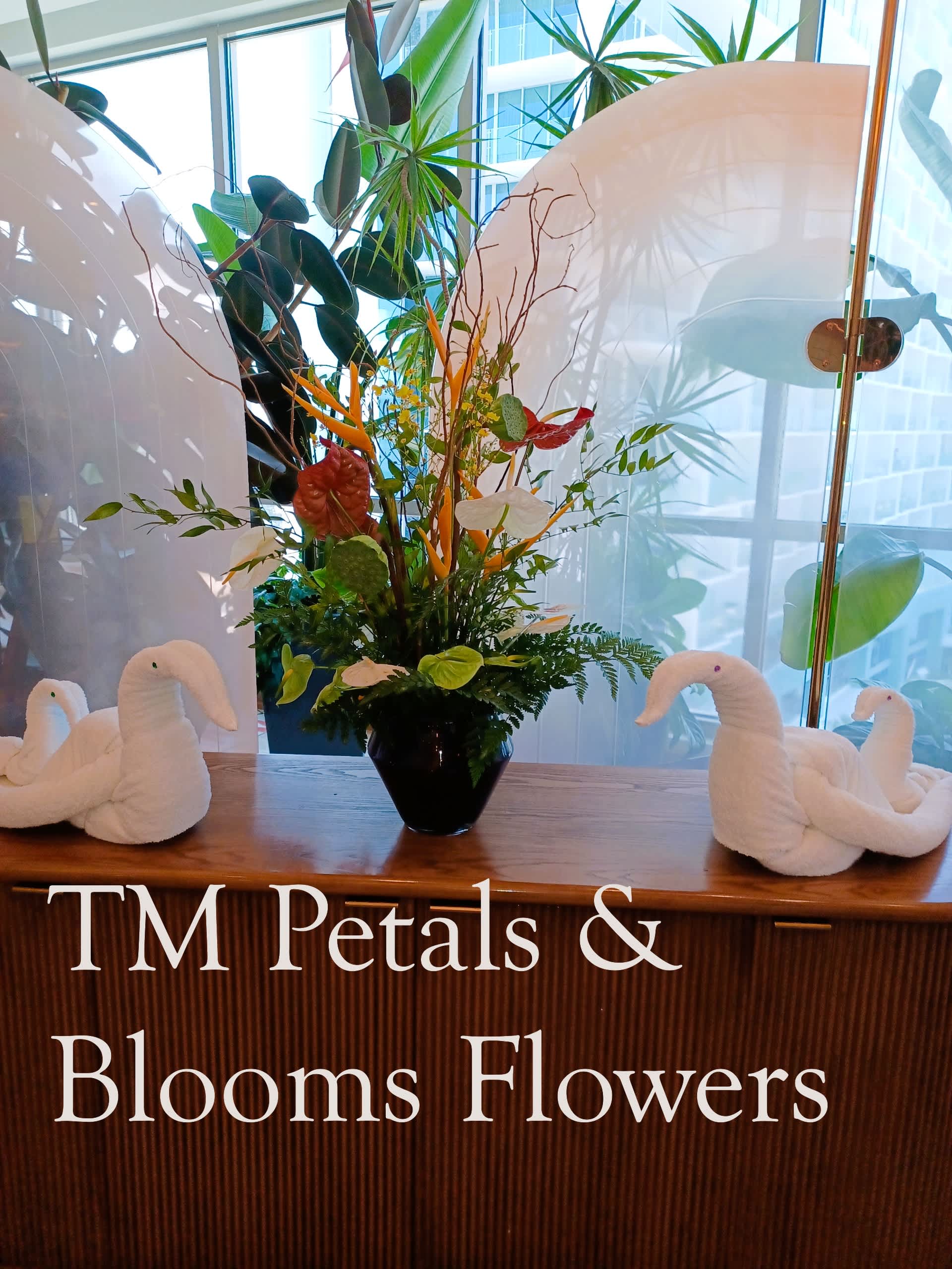 Tropical flower arrangement in a black vase with white swan decorations