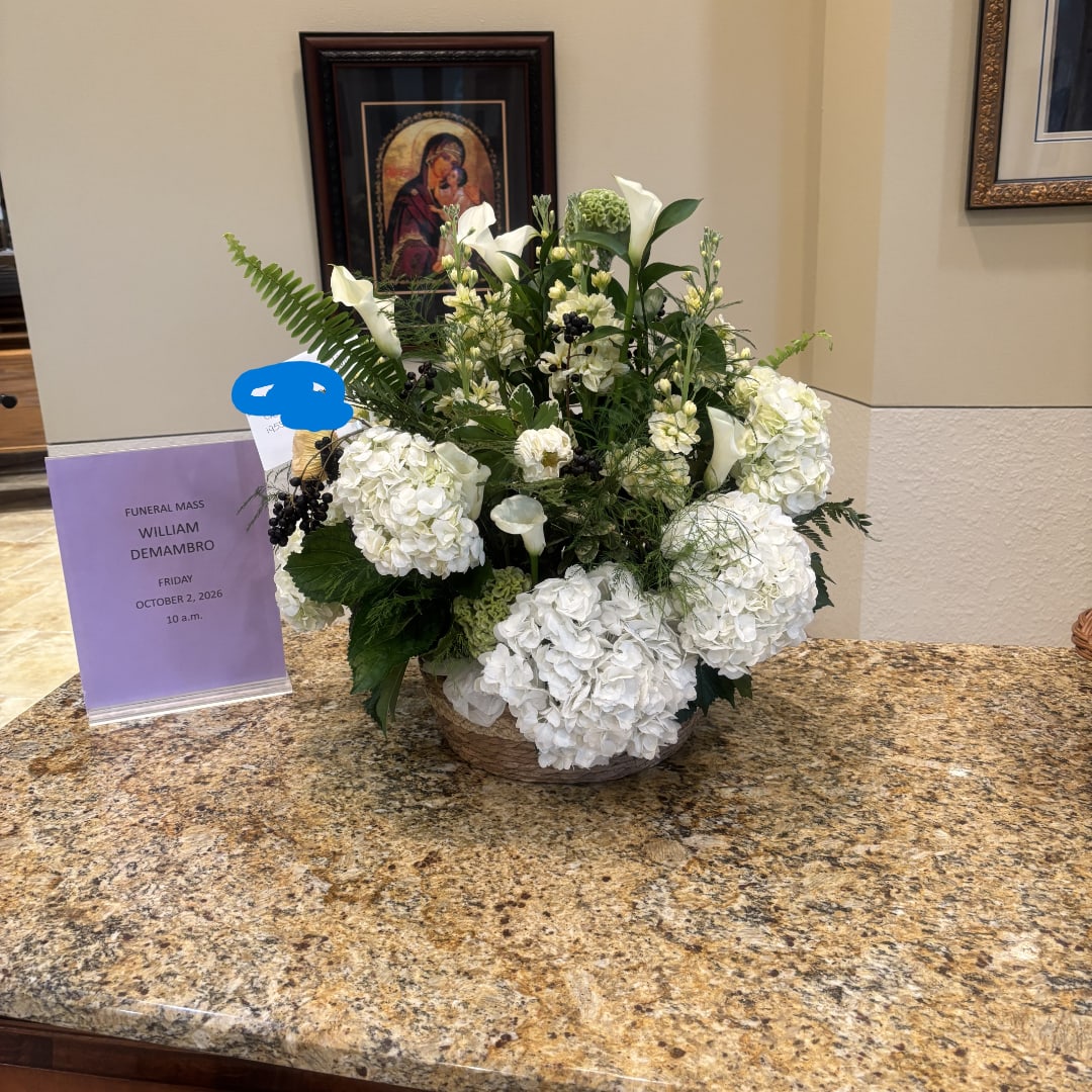 White floral arrangement in a low basket with calla lilies and hydrangeas