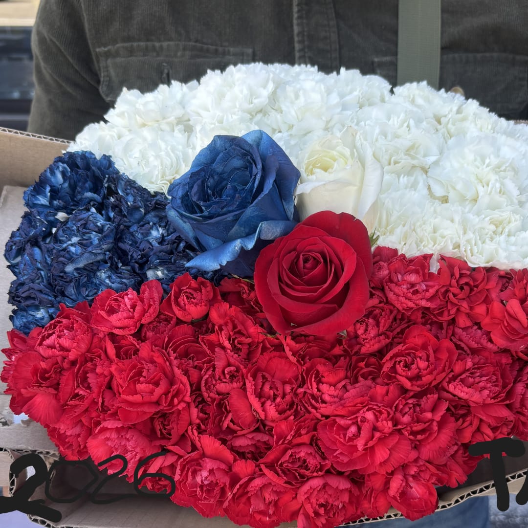 Red, white, and blue floral arrangement in a cardboard box