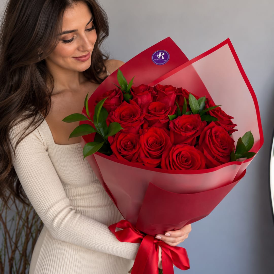 Woman holding a bouquet of red roses wrapped in red paper