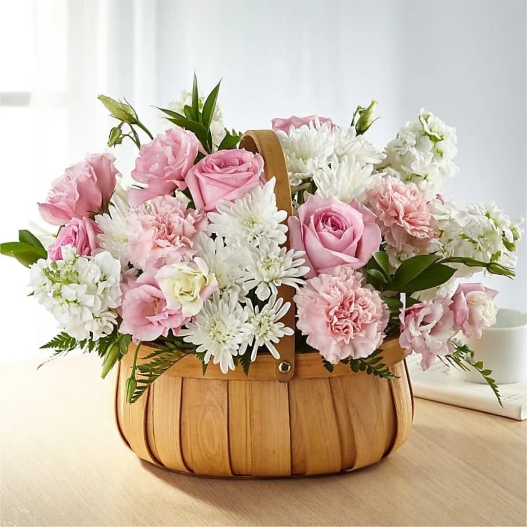 Pink and white flowers arranged in a wooden basket