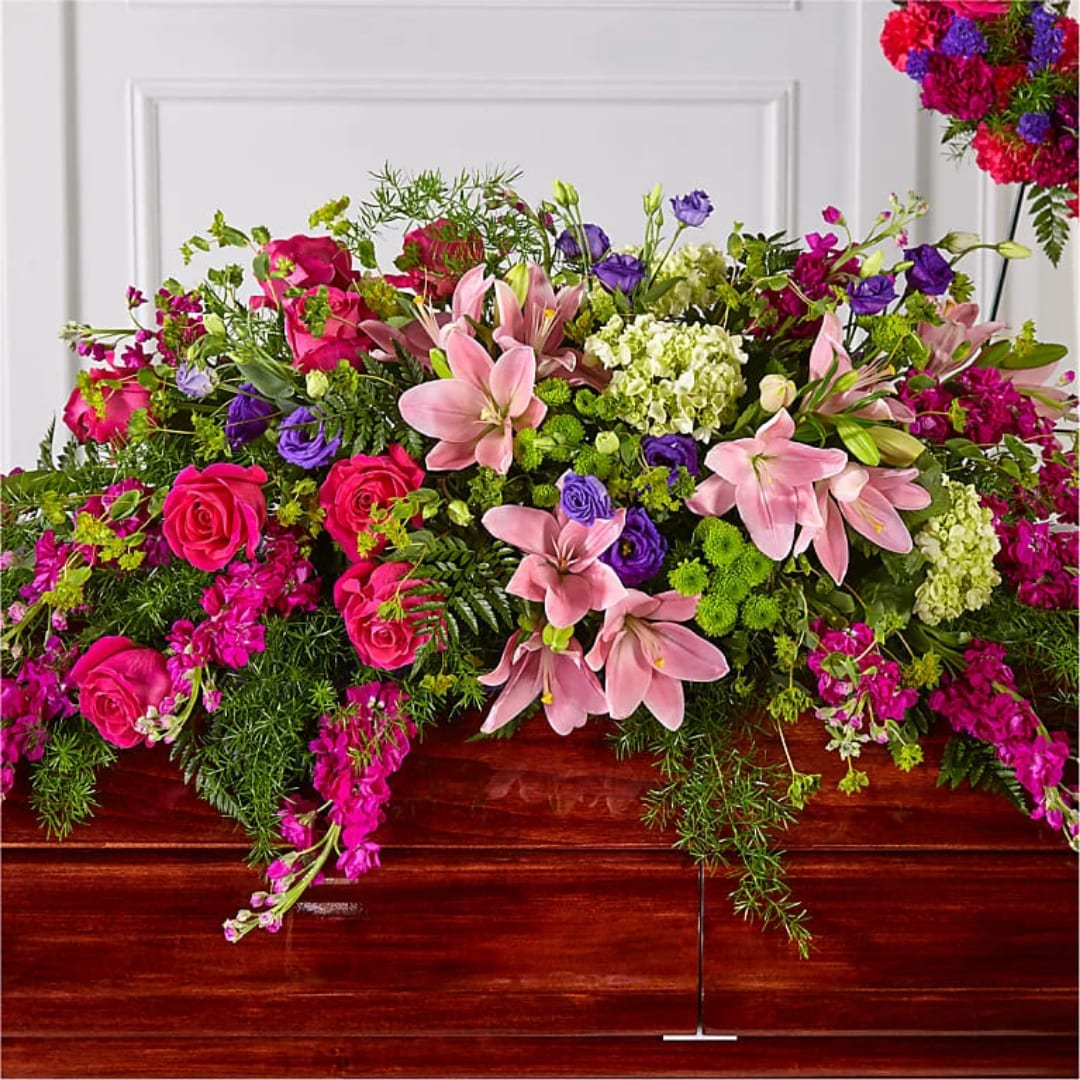 Large floral casket spray with pink lilies, roses, and purple blooms