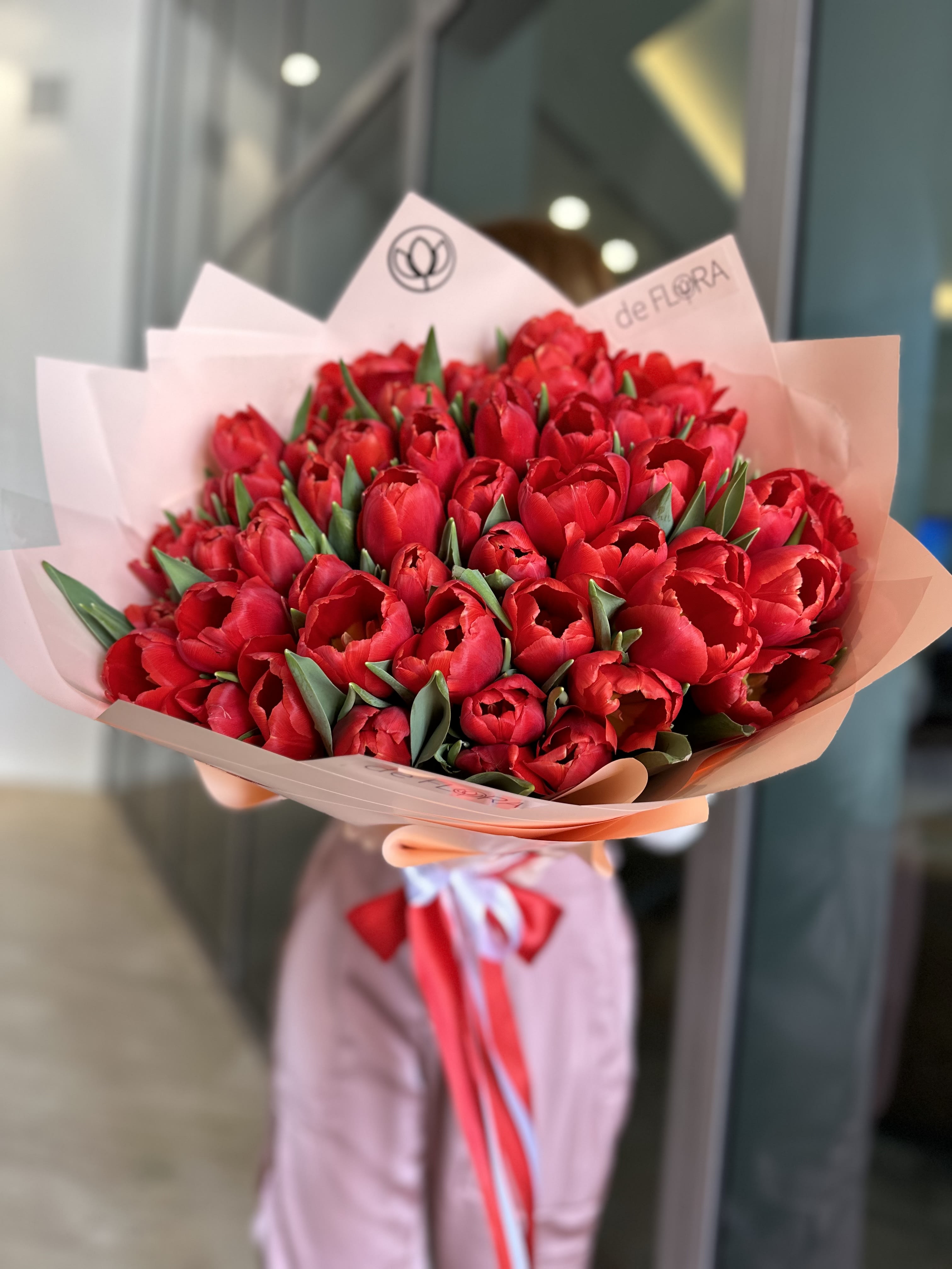 Bouquet of red tulips wrapped in pale pink paper