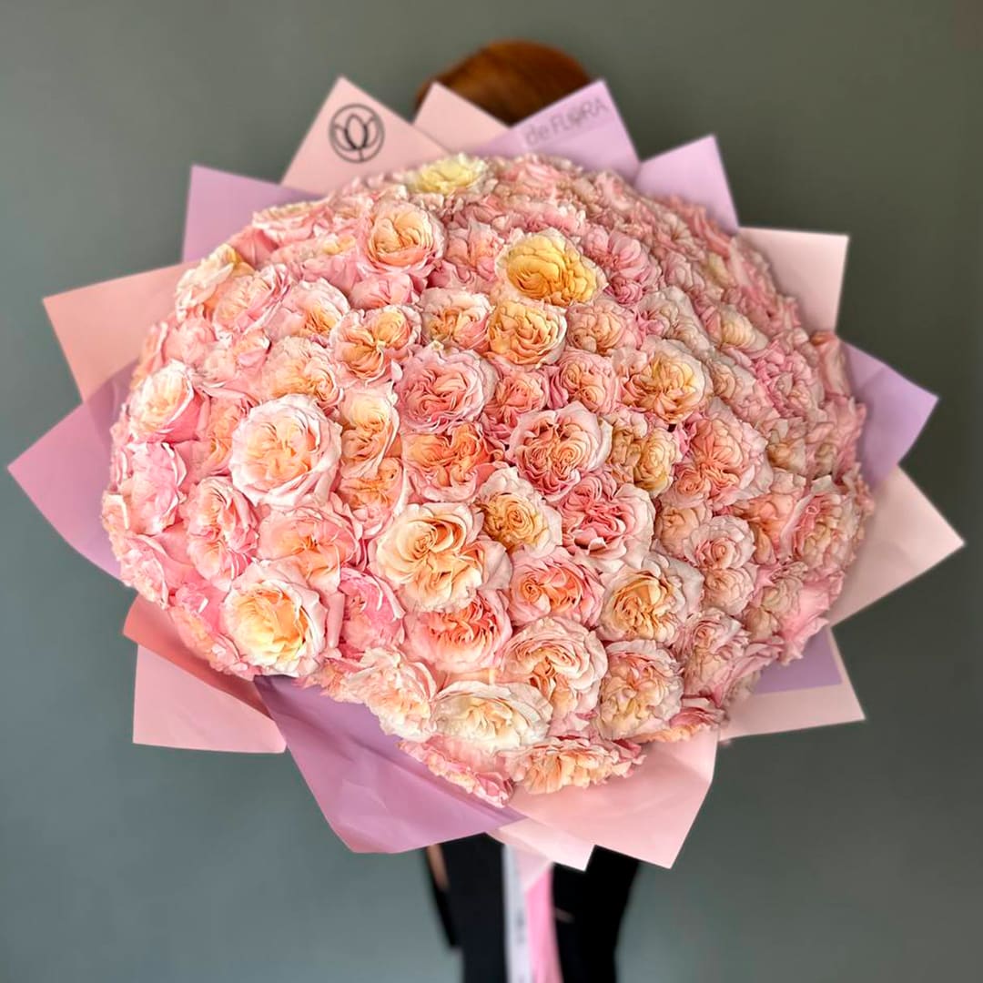Large bouquet of pale pink and peach roses wrapped in pink paper
