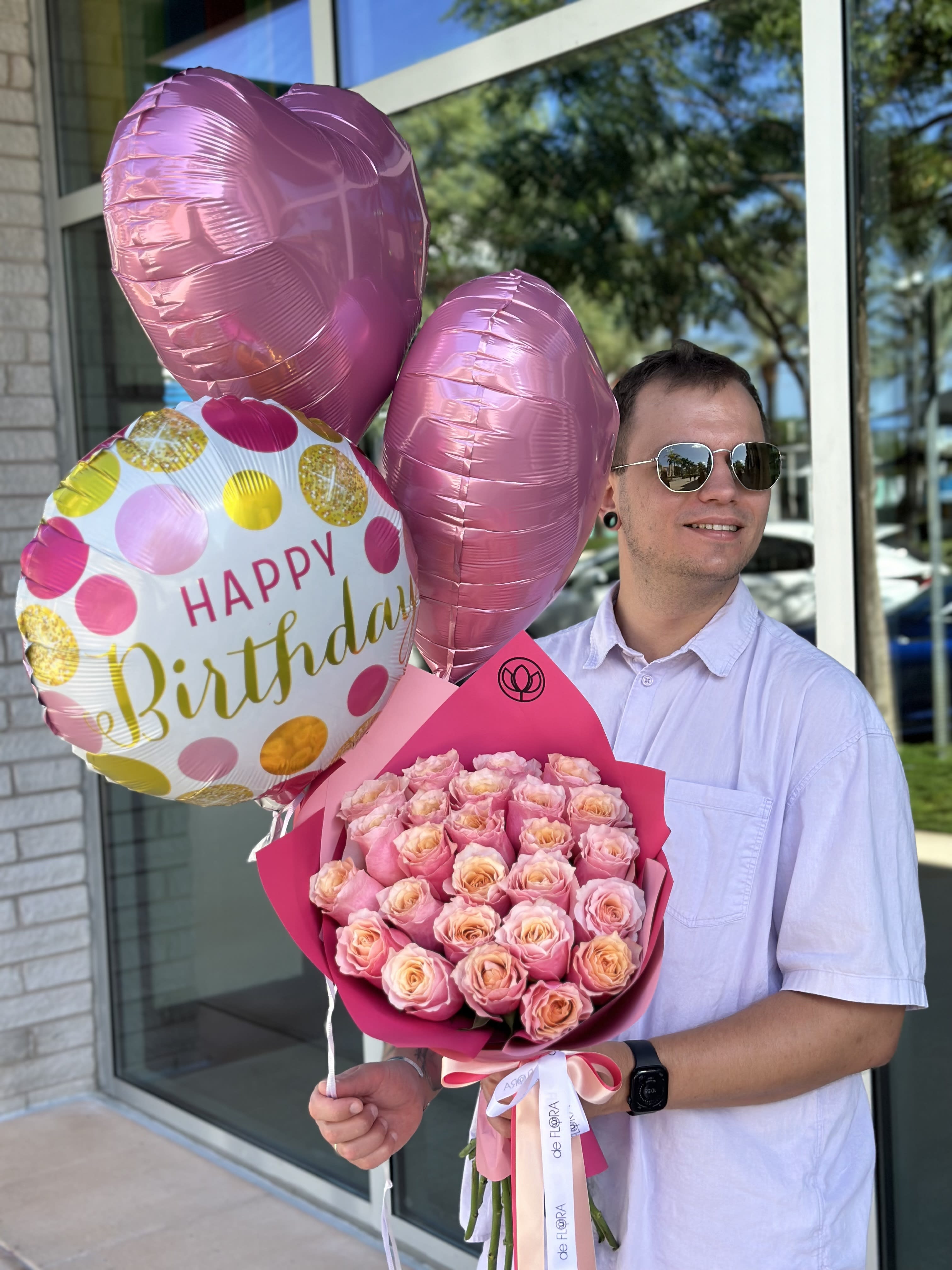 Man holding pink rose bouquet and birthday balloons
